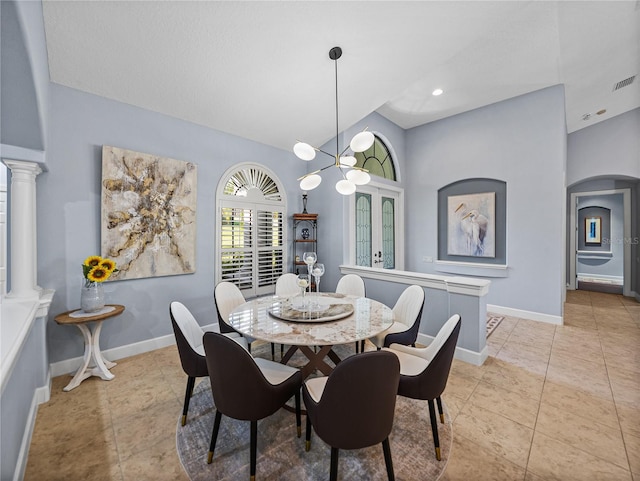 dining space with light tile patterned flooring, baseboards, arched walkways, and ornate columns