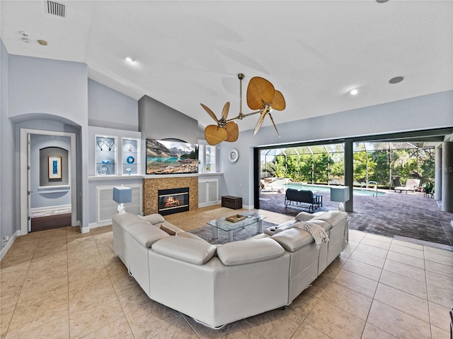 living room featuring vaulted ceiling, light tile patterned floors, visible vents, a tile fireplace, and built in features