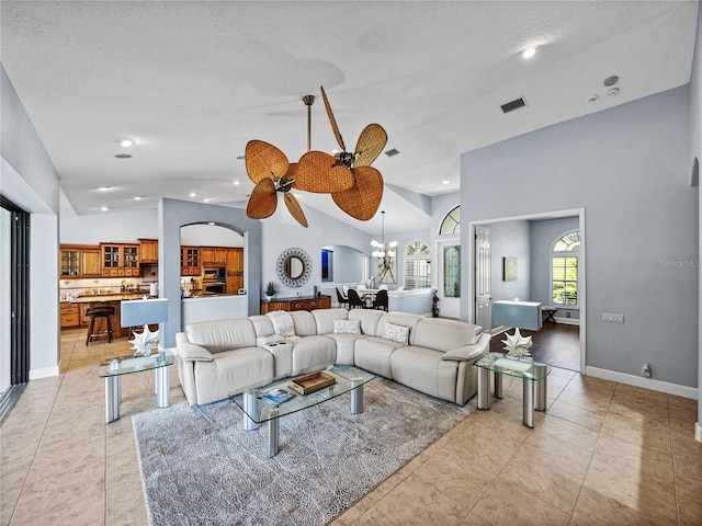 living area featuring arched walkways, a textured ceiling, visible vents, and ceiling fan with notable chandelier