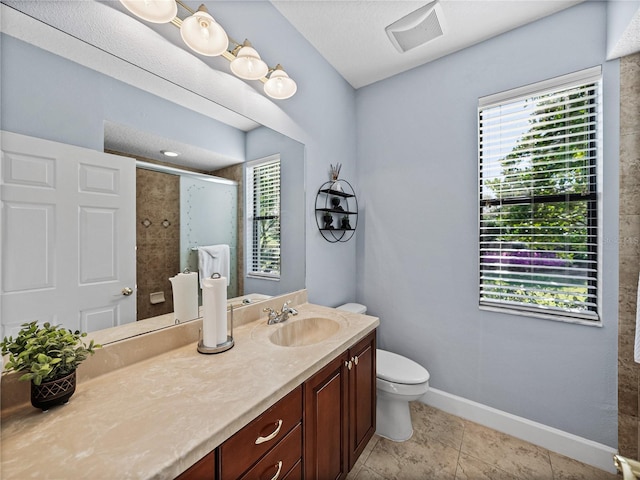 full bath with a tile shower, toilet, vanity, tile patterned flooring, and baseboards