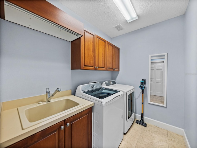 laundry room featuring independent washer and dryer, a textured ceiling, a sink, visible vents, and cabinet space