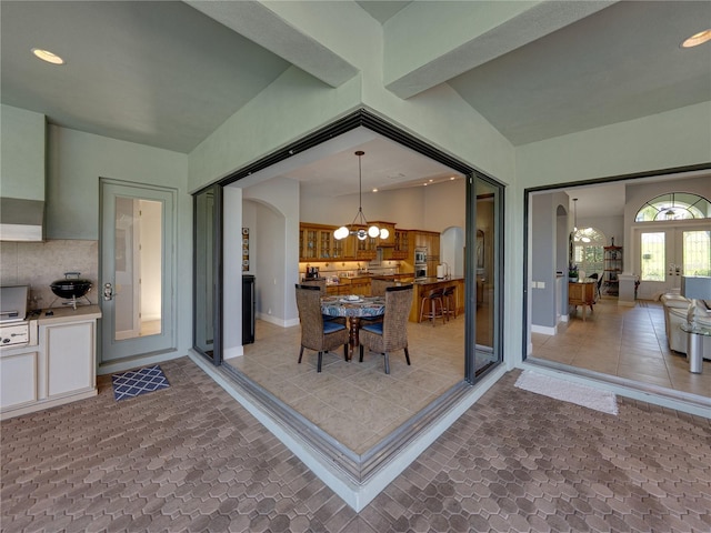 unfurnished dining area with arched walkways, light tile patterned flooring, baseboards, and a notable chandelier
