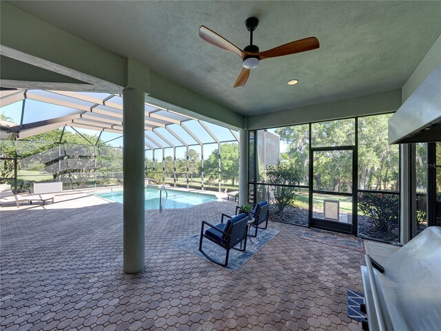 pool featuring glass enclosure, a patio, and a ceiling fan