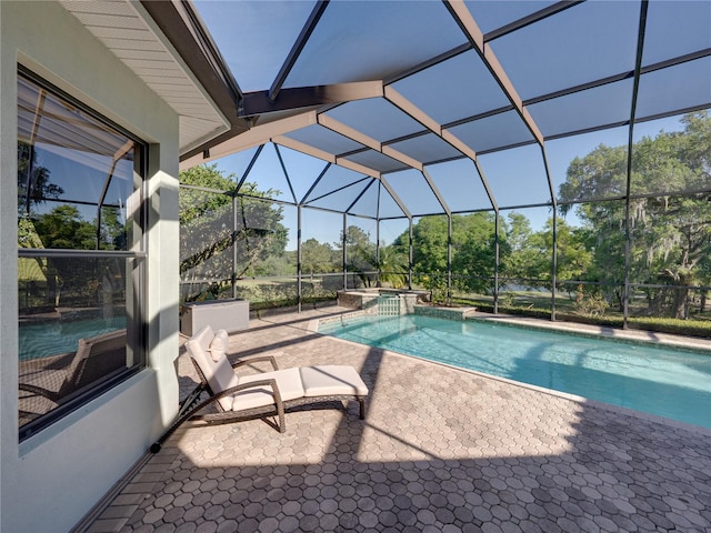 view of swimming pool featuring glass enclosure, a pool with connected hot tub, and a patio area