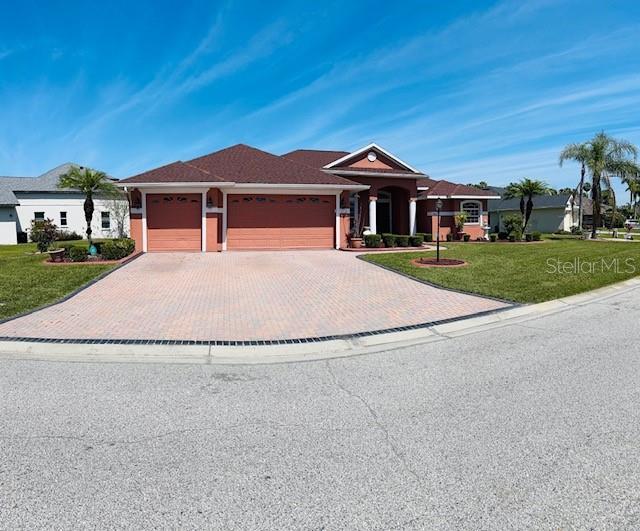 view of front of property with an attached garage, decorative driveway, and a front yard