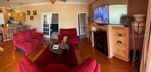 living area featuring ceiling fan, wood finished floors, and crown molding