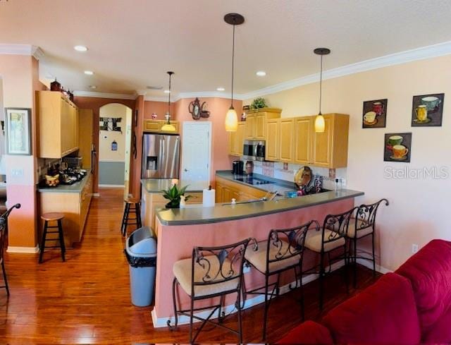 kitchen with dark wood-type flooring, appliances with stainless steel finishes, a peninsula, and a breakfast bar