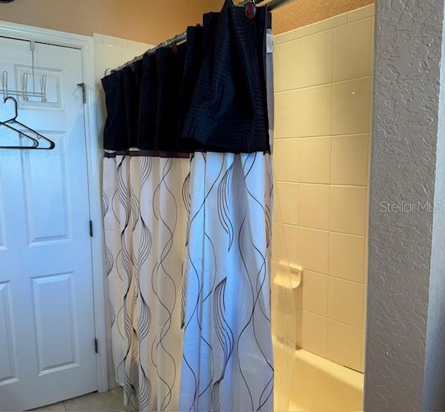 full bathroom featuring shower / tub combo with curtain and a textured wall