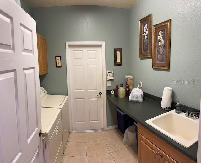 laundry room featuring separate washer and dryer, light tile patterned floors, cabinet space, and a sink