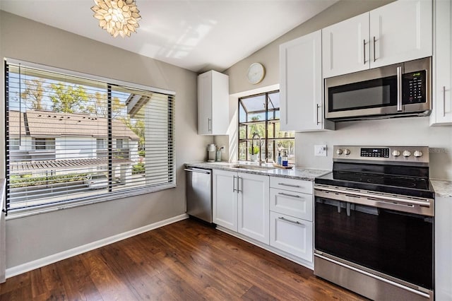 kitchen with a sink, vaulted ceiling, dark wood-type flooring, appliances with stainless steel finishes, and white cabinetry