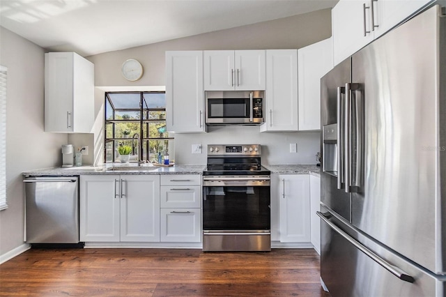 kitchen with dark wood-style floors, a sink, stainless steel appliances, vaulted ceiling, and white cabinetry