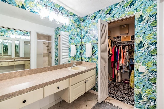 full bath featuring vanity, wallpapered walls, tile patterned flooring, a shower stall, and a spacious closet