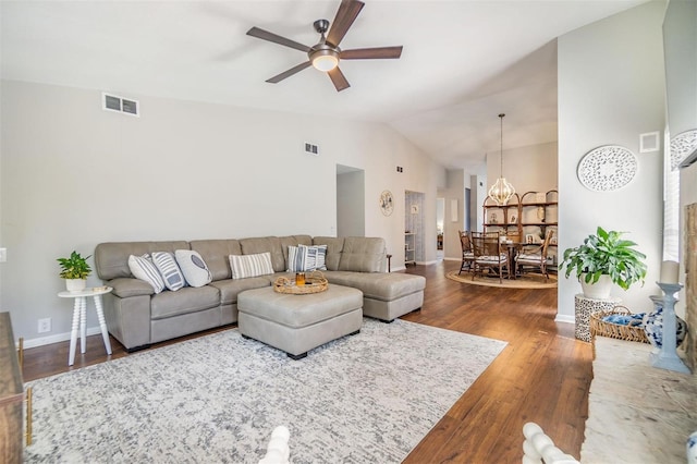 living area with wood finished floors, visible vents, baseboards, high vaulted ceiling, and ceiling fan with notable chandelier