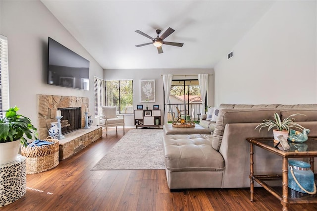 living area with a ceiling fan, visible vents, high vaulted ceiling, dark wood finished floors, and a stone fireplace