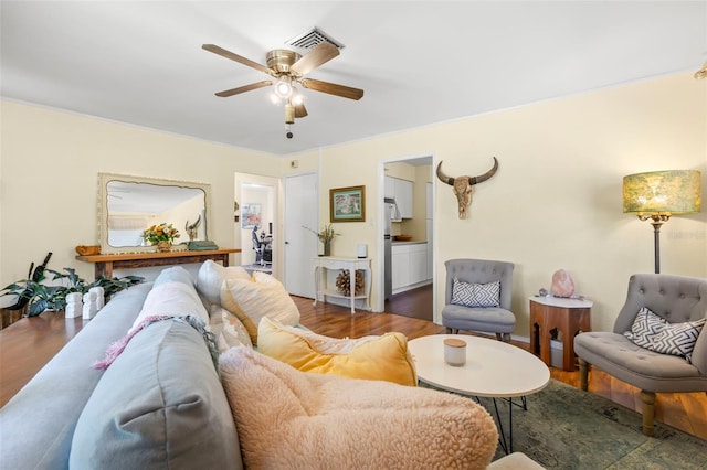 living area with visible vents, wood finished floors, and a ceiling fan