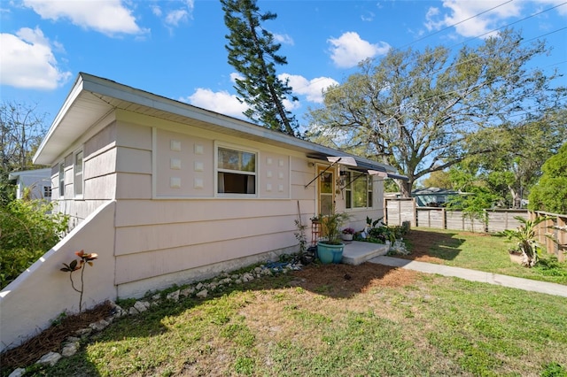 view of property exterior featuring a lawn and fence