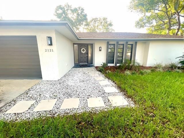 view of exterior entry featuring concrete driveway, a garage, and stucco siding