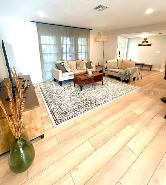 living area with light wood-style floors and visible vents