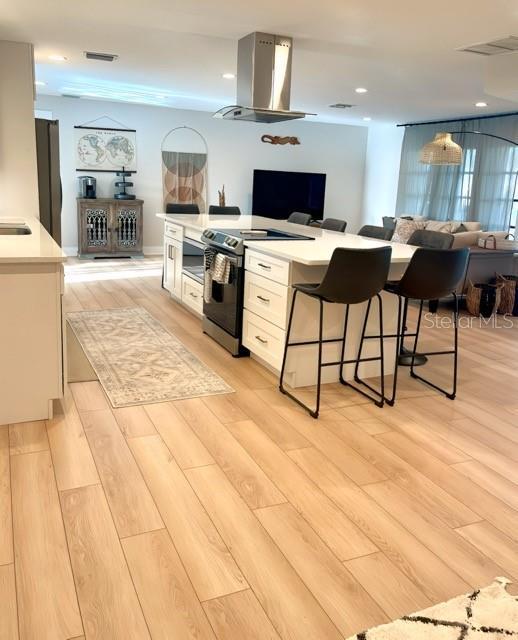 kitchen with visible vents, ventilation hood, electric stove, and open floor plan