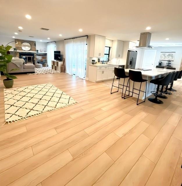 living area with a fireplace, recessed lighting, visible vents, and light wood finished floors