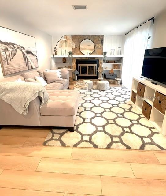 living area featuring visible vents, wood finished floors, and a fireplace