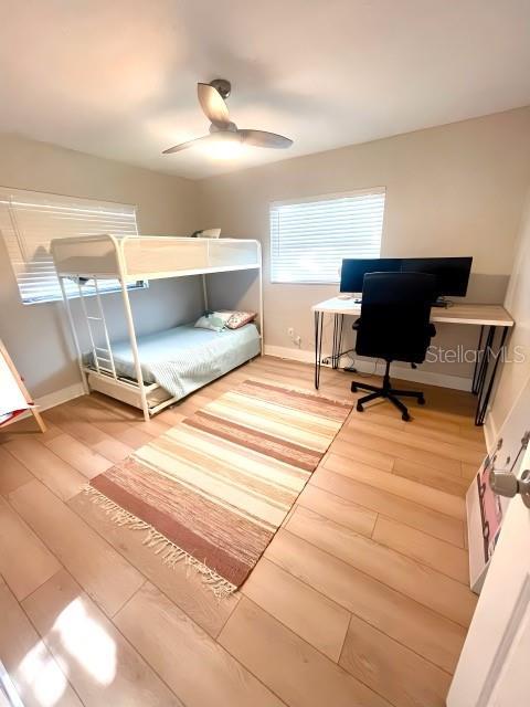 bedroom with baseboards, light wood-type flooring, and ceiling fan