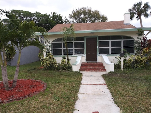 view of front of house with stucco siding, entry steps, and a front yard