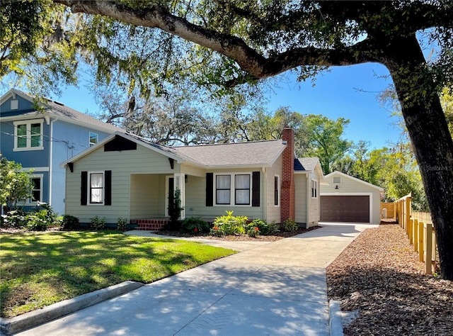 view of front of home with driveway, a front lawn, fence, an outdoor structure, and a chimney