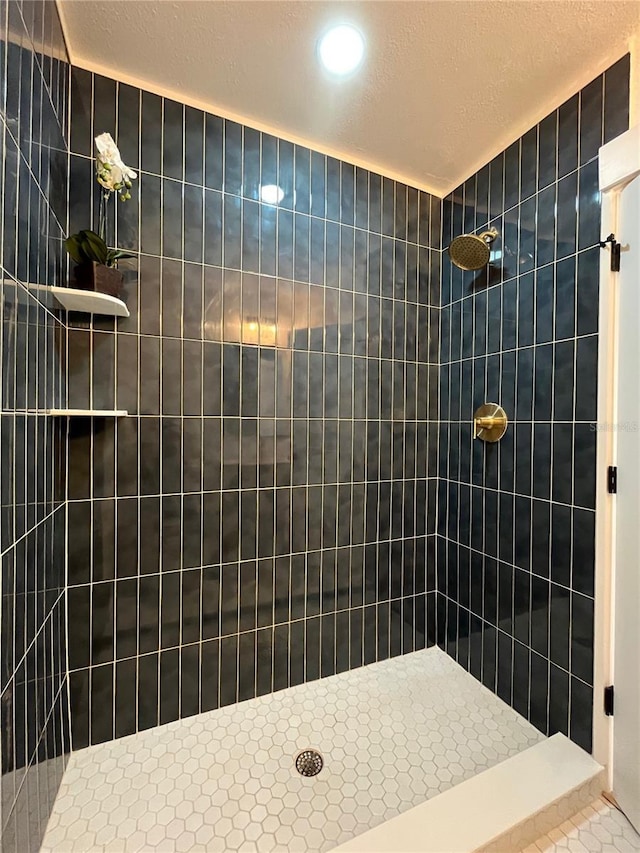 bathroom featuring a tile shower and a textured ceiling