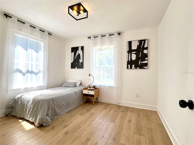 bedroom with baseboards and light wood finished floors