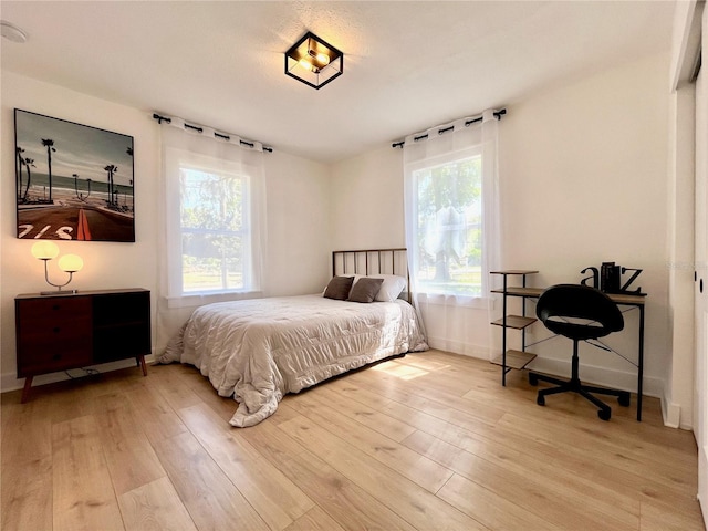 bedroom featuring light wood finished floors and baseboards