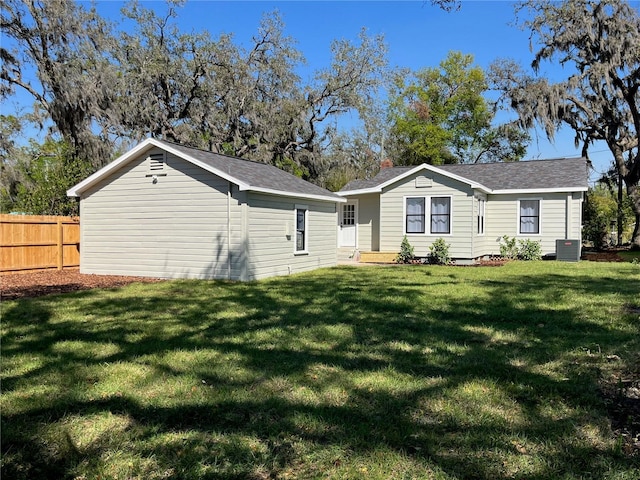 back of property featuring a yard, central AC, and fence