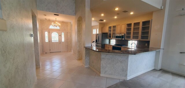 7279 Maidencane Ct, Seminole, FL 33777 - kitchen with a notable chandelier, dark stone countertops, appliances with stainless steel finishes, light tile patterned floors, and glass insert cabinets