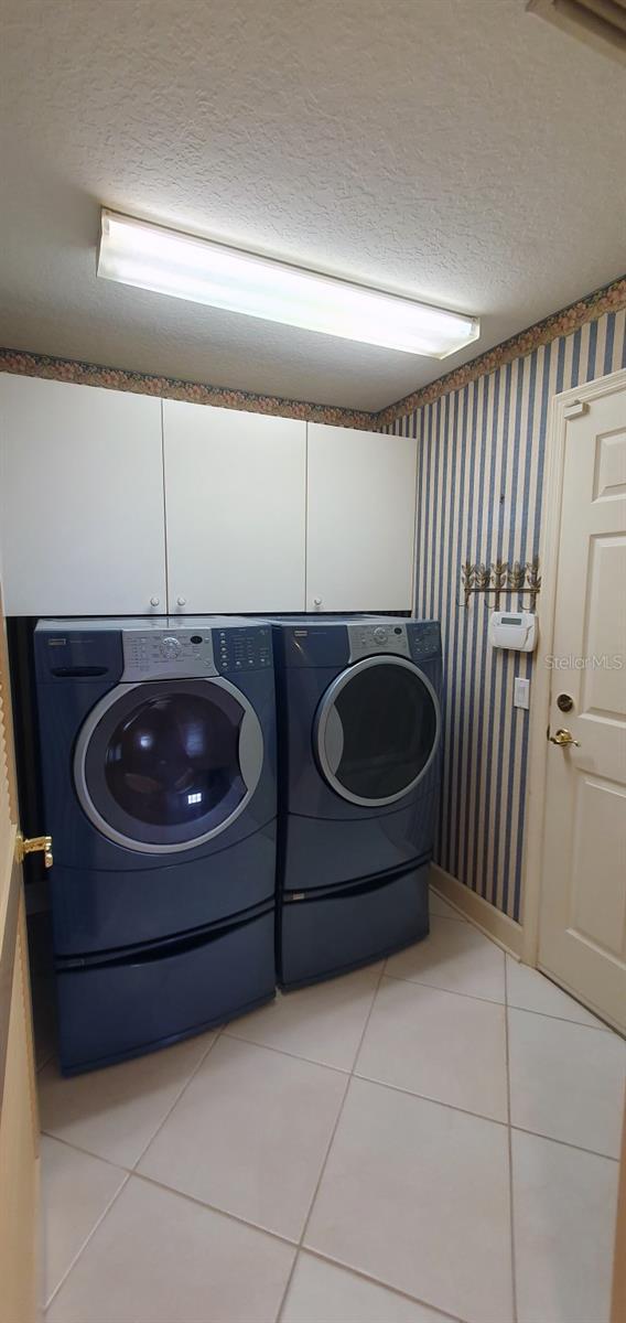 7279 Maidencane Ct, Seminole, FL 33777 - washroom featuring light tile patterned floors, a textured ceiling, independent washer and dryer, and wallpapered walls