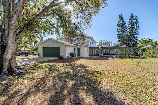 view of front of home featuring a front lawn, concrete driveway, glass enclosure, cooling unit, and a garage