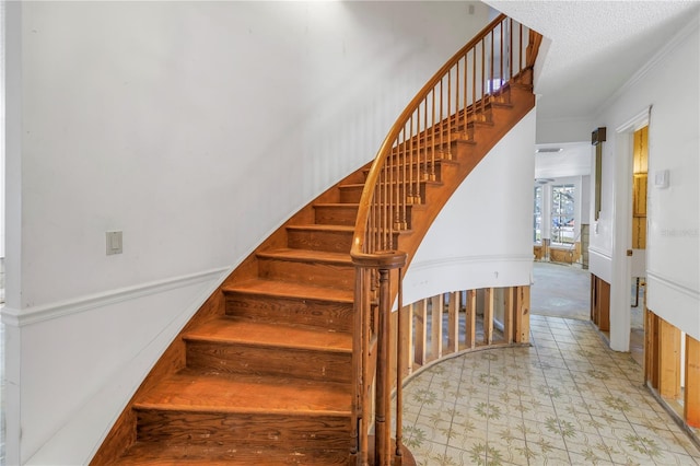 staircase with a textured ceiling and crown molding