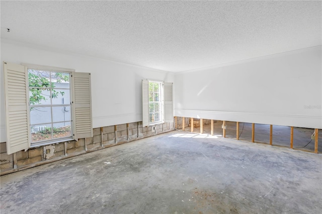 empty room with a textured ceiling and concrete flooring