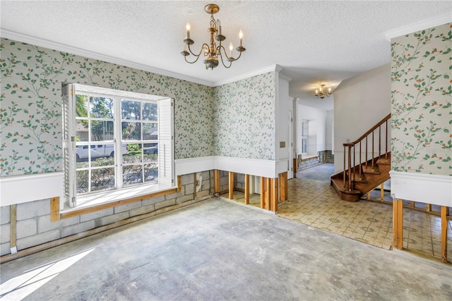 unfurnished dining area featuring wallpapered walls, a chandelier, ornamental molding, wainscoting, and a textured ceiling