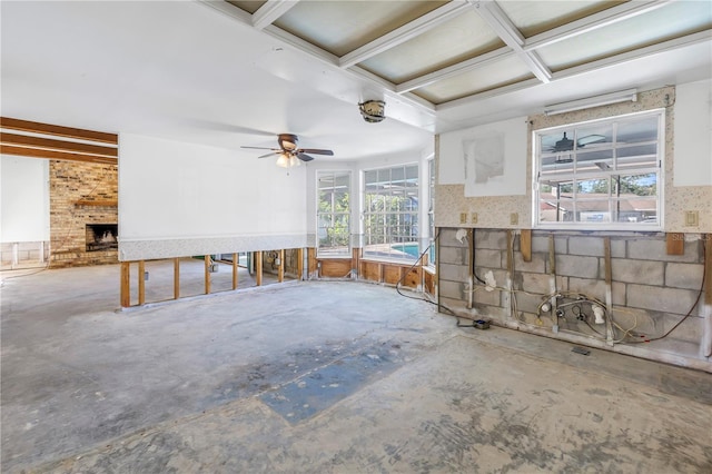 unfurnished living room with a brick fireplace, a healthy amount of sunlight, concrete floors, and ceiling fan