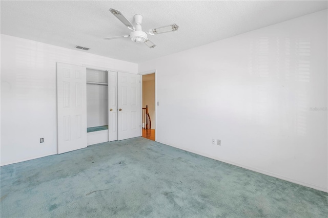 unfurnished bedroom with a textured ceiling, carpet flooring, visible vents, and ceiling fan