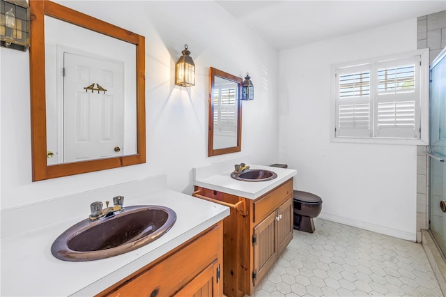 bathroom with two vanities, toilet, an enclosed shower, and a sink