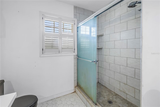 bathroom featuring baseboards, toilet, and a stall shower