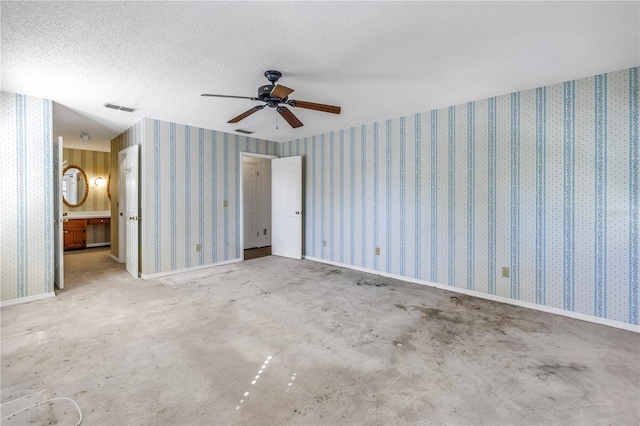 unfurnished bedroom featuring wallpapered walls, visible vents, and a textured ceiling