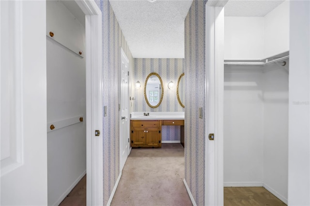 interior space featuring wallpapered walls, light carpet, baseboards, and a textured ceiling