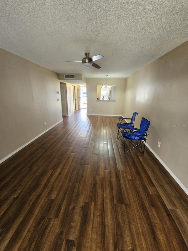 unfurnished room with visible vents, baseboards, dark wood-type flooring, and ceiling fan with notable chandelier