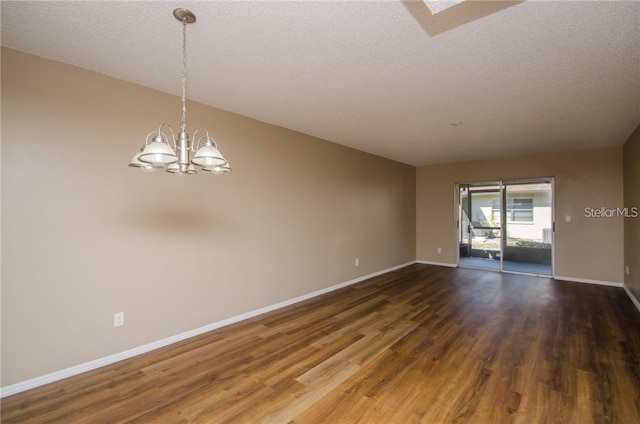 spare room with baseboards, a notable chandelier, dark wood finished floors, and a textured ceiling