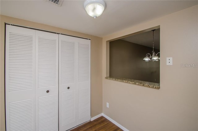 corridor featuring dark wood finished floors, visible vents, a chandelier, and baseboards