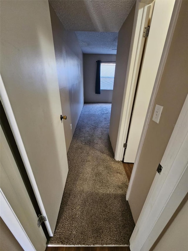 corridor with carpet floors and a textured ceiling