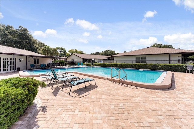 pool with french doors, a patio, and fence