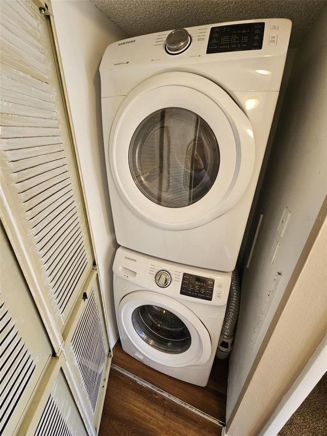 washroom featuring laundry area, a textured ceiling, stacked washer / drying machine, and wood finished floors